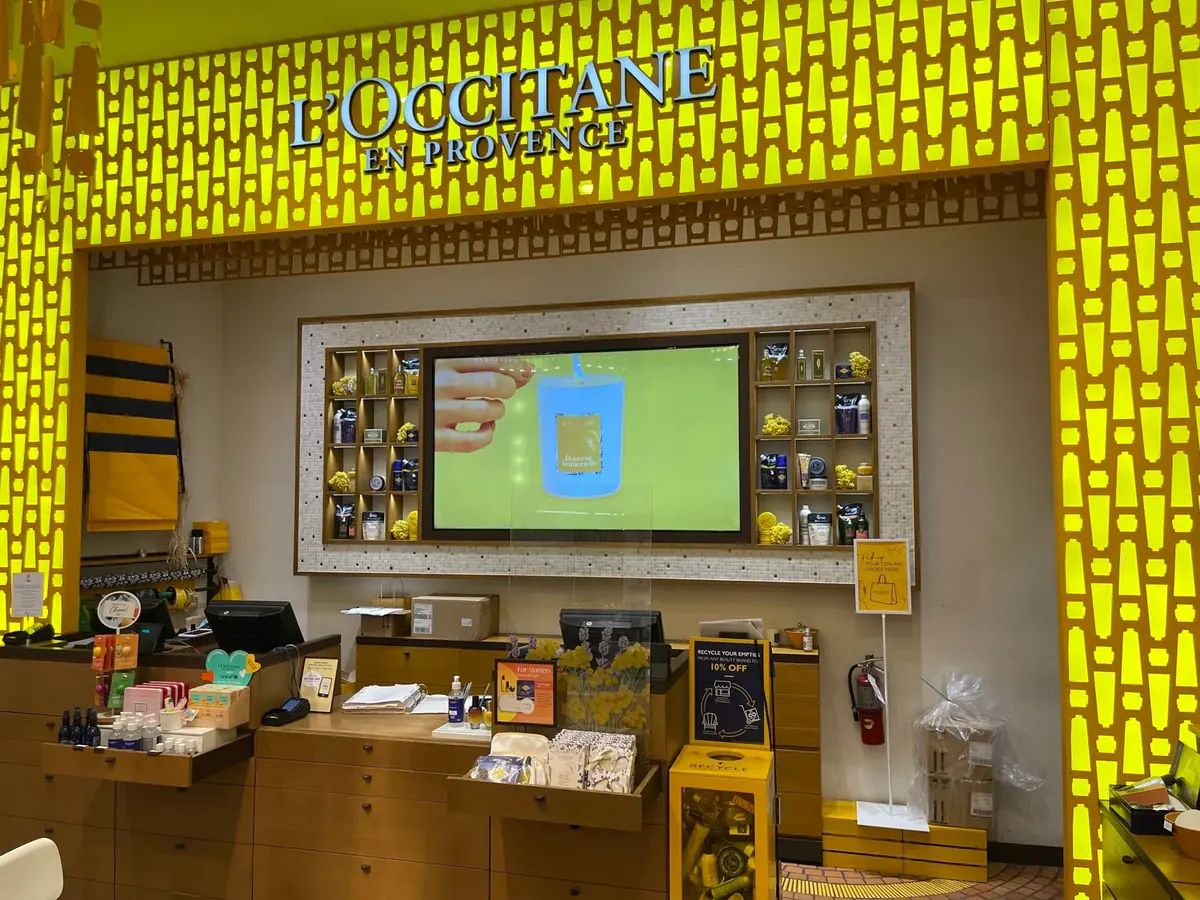 L'Occitane boutique with a feature wall display above the counter