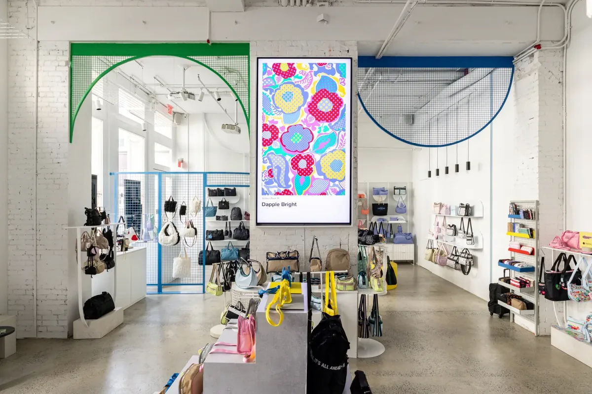 LeSportsac SoHo sales floor with a 98-inch in-store display framed in white millwork